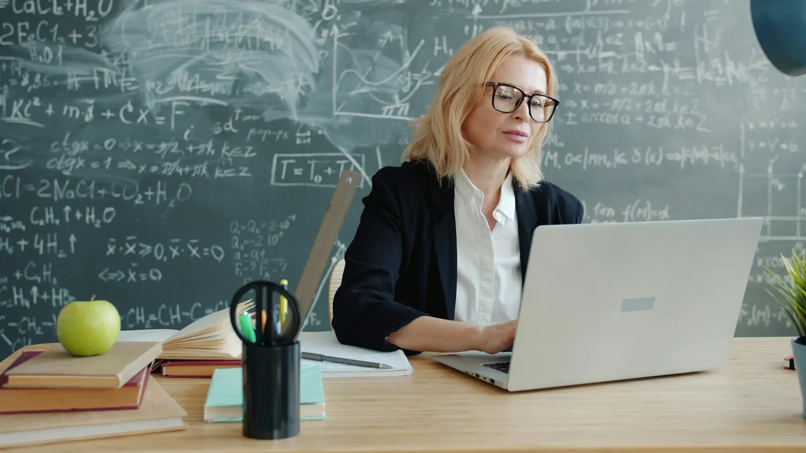 An educator reviewing work on a laptop in a classroom